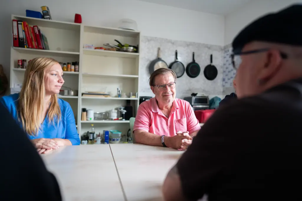 Mehrere Personen sitzen an einem Tisch und unterhalten sich.