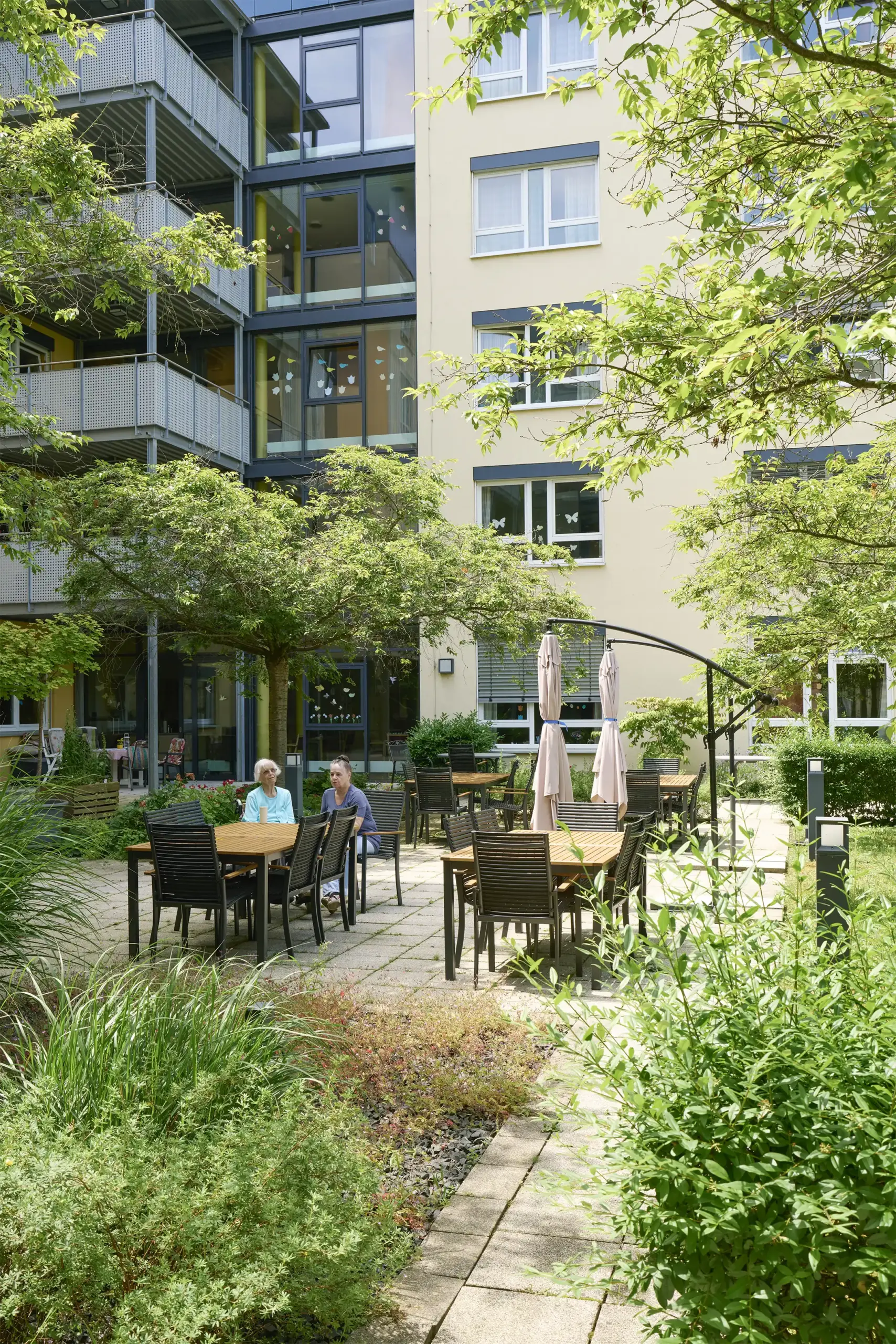 Zwei Frauen sitzen an einem Tisch im Garten des Hauses Karlsruher Weg.