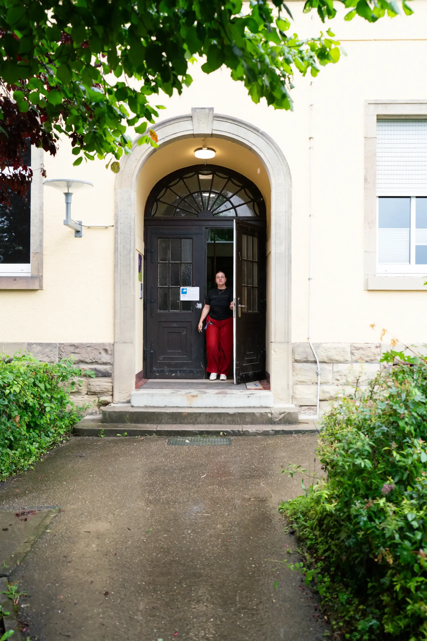 Eine Frau tritt aus einer Tür.