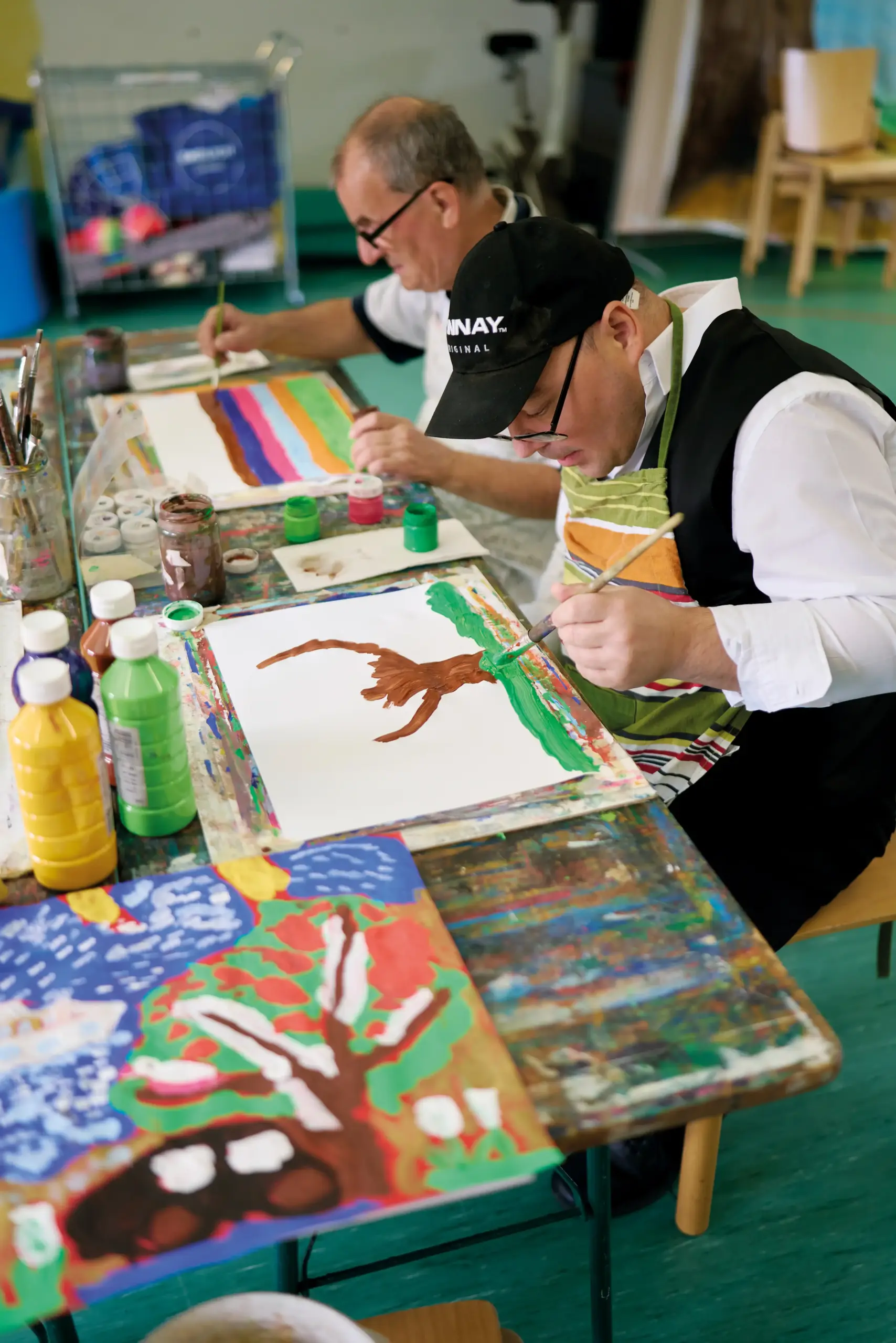 Zwei Männer sitzen an einem Tisch und malen.