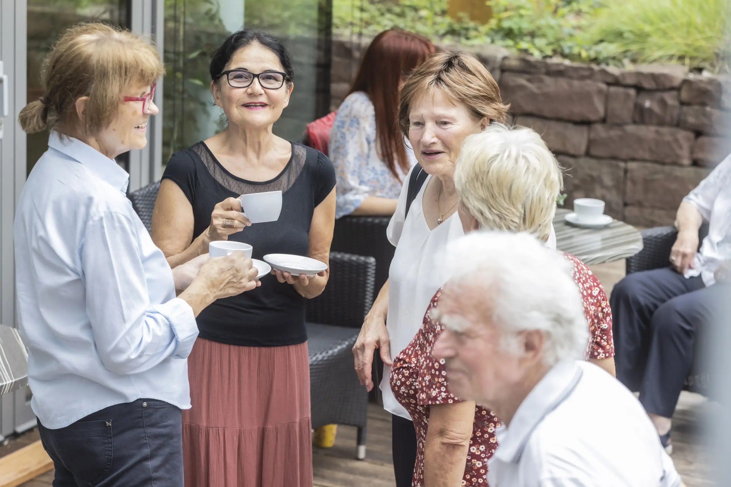Quelle: BLV Vier Frauen stehen beieinander. Zwei von ihnen haben Kaffeetassen in der Hand. Sie lachen.