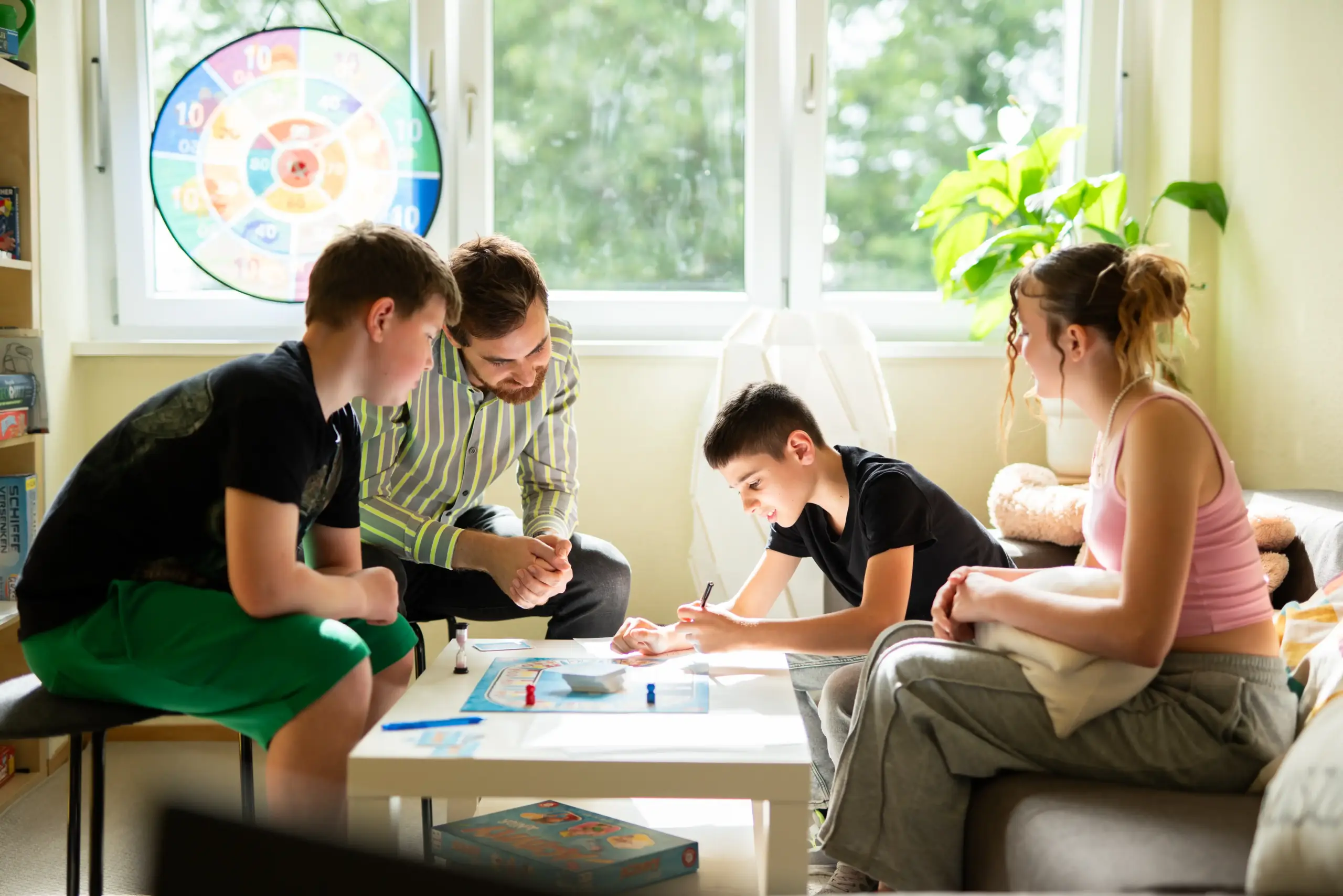 Drei Jugendliche spielen gemeinsam mit einem Mann ein Spiel.