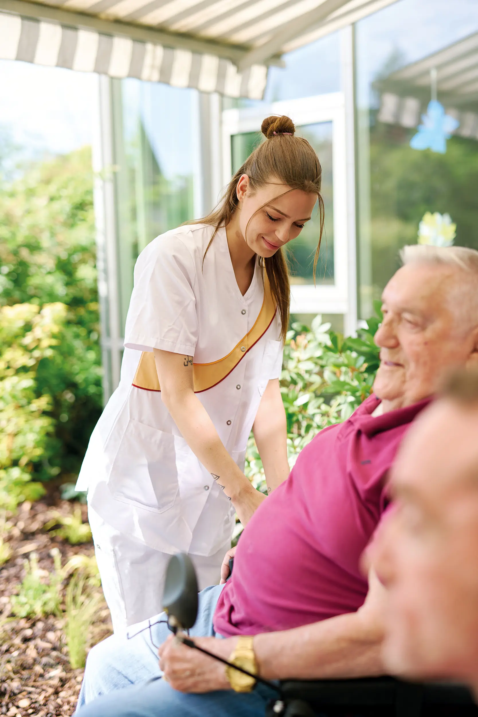 Quelle: BLV Eine Pflegerin kümmert sich um zwei Männer im Rollstuhl.
