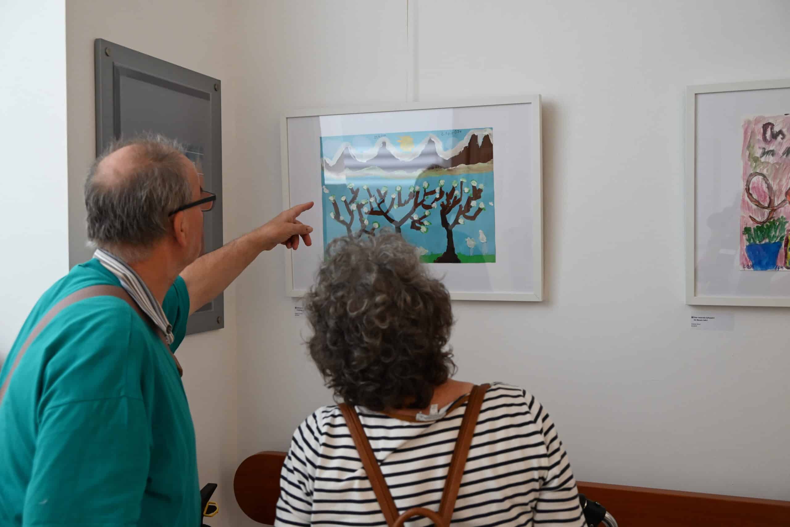 Ein Mann und eine Frau betrachten ein Bild. Der Mann zeigt auf das Bild.