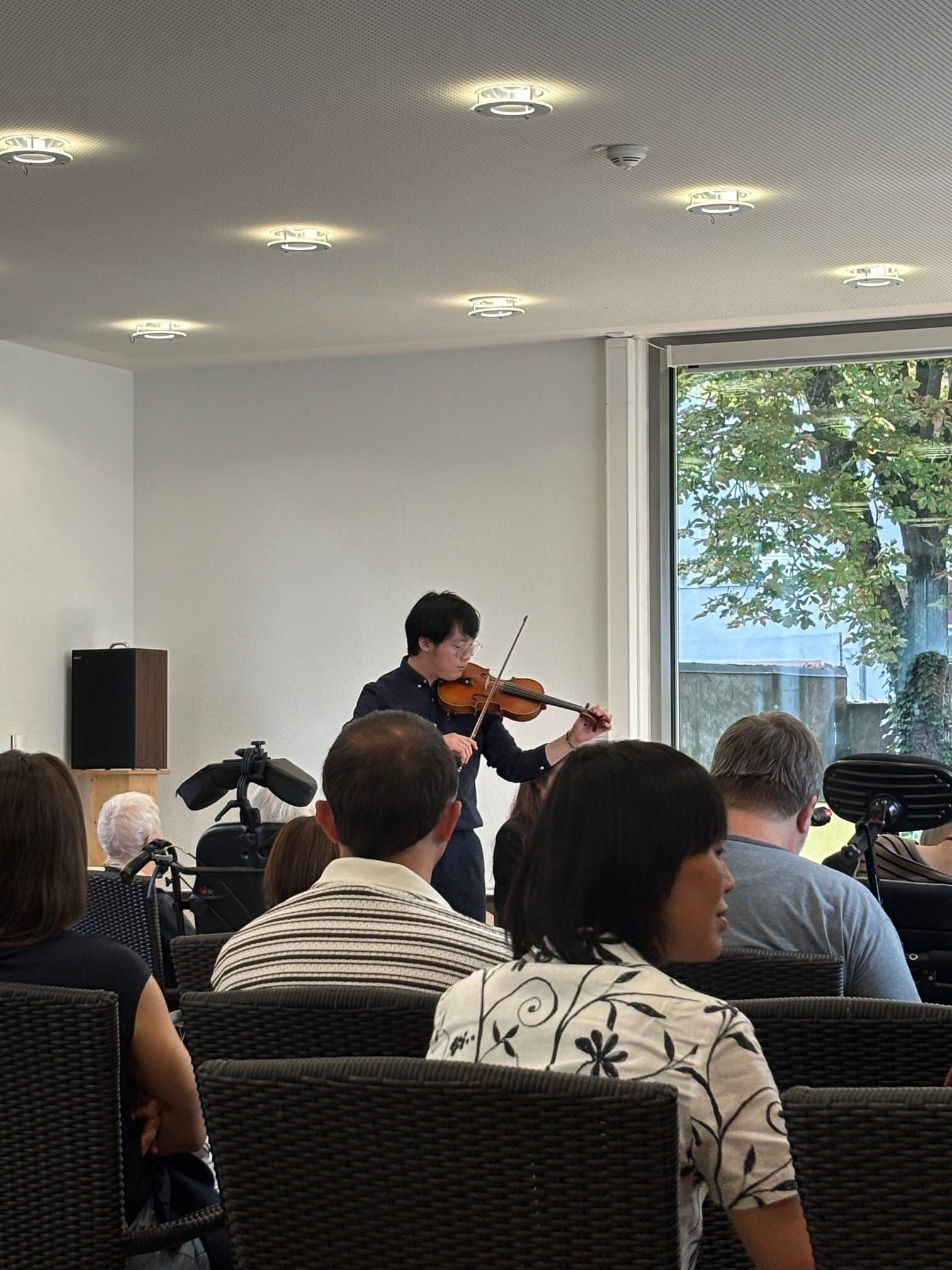 Ein Mann spielt vor einem Publikum auf seiner Geige.