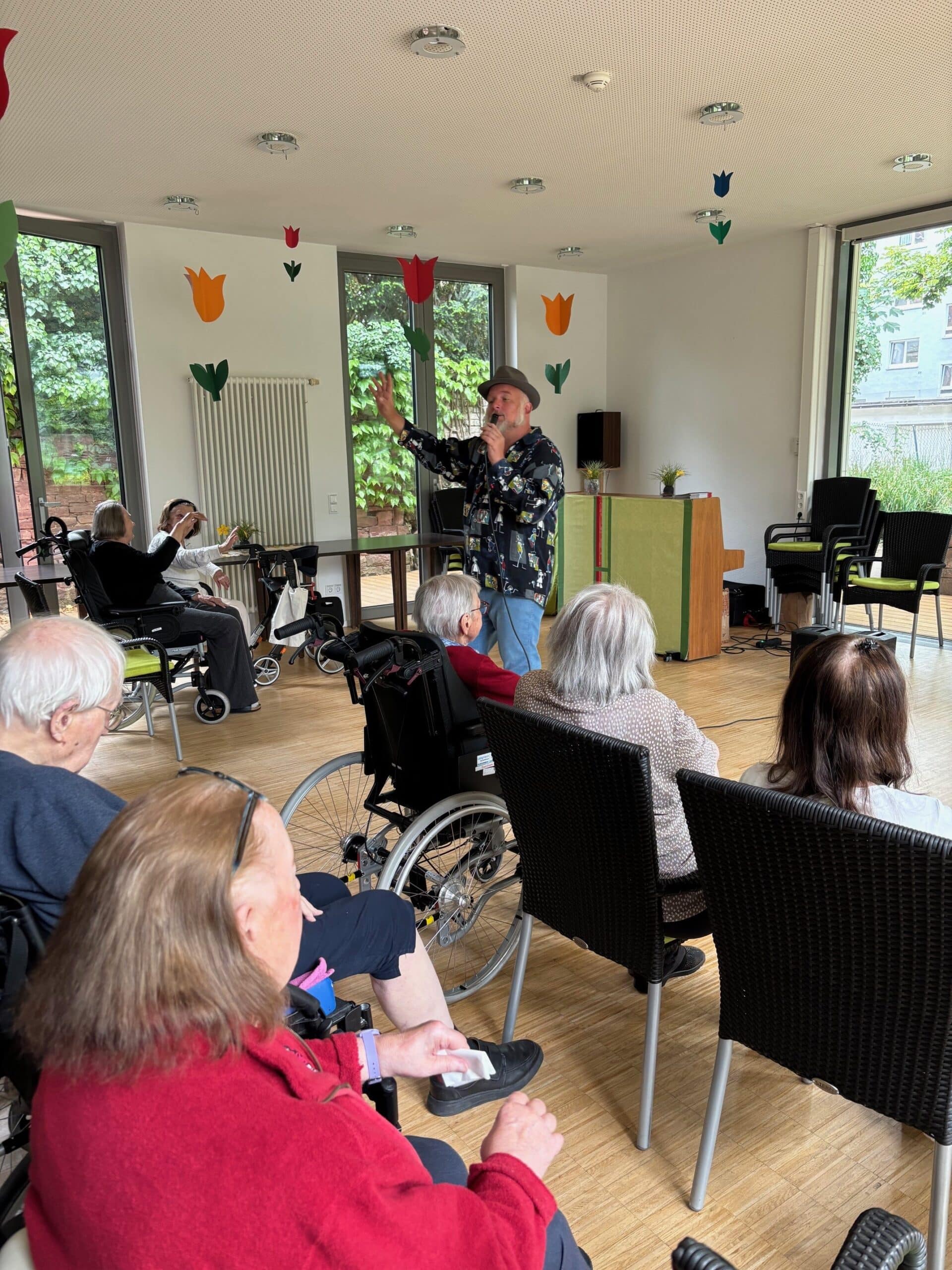 Ein Mann mit Hut steht vor einem Publikum und singt.