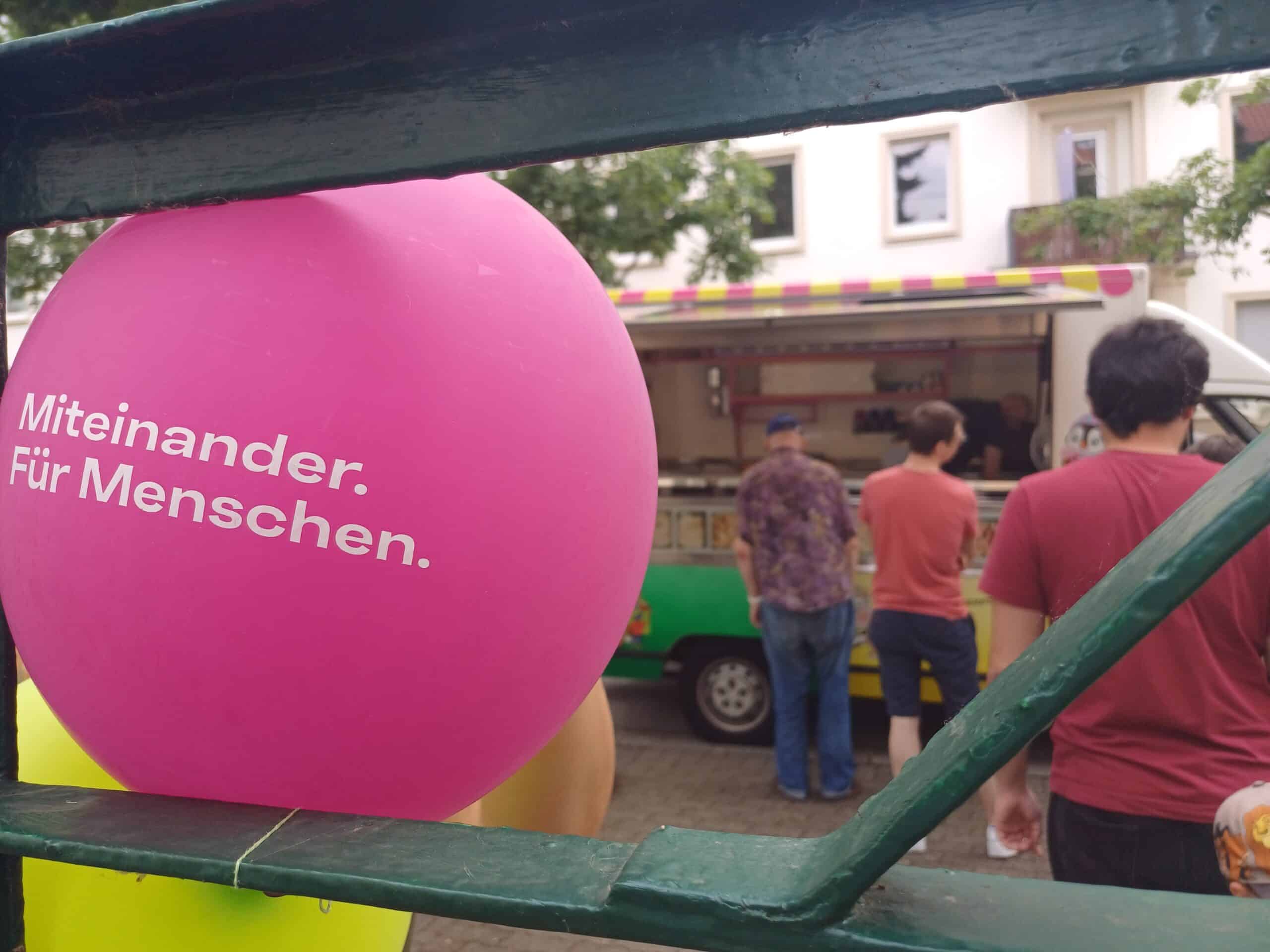 Im Vordergrund ein violetter Luftballon mit der Aufschrift 
