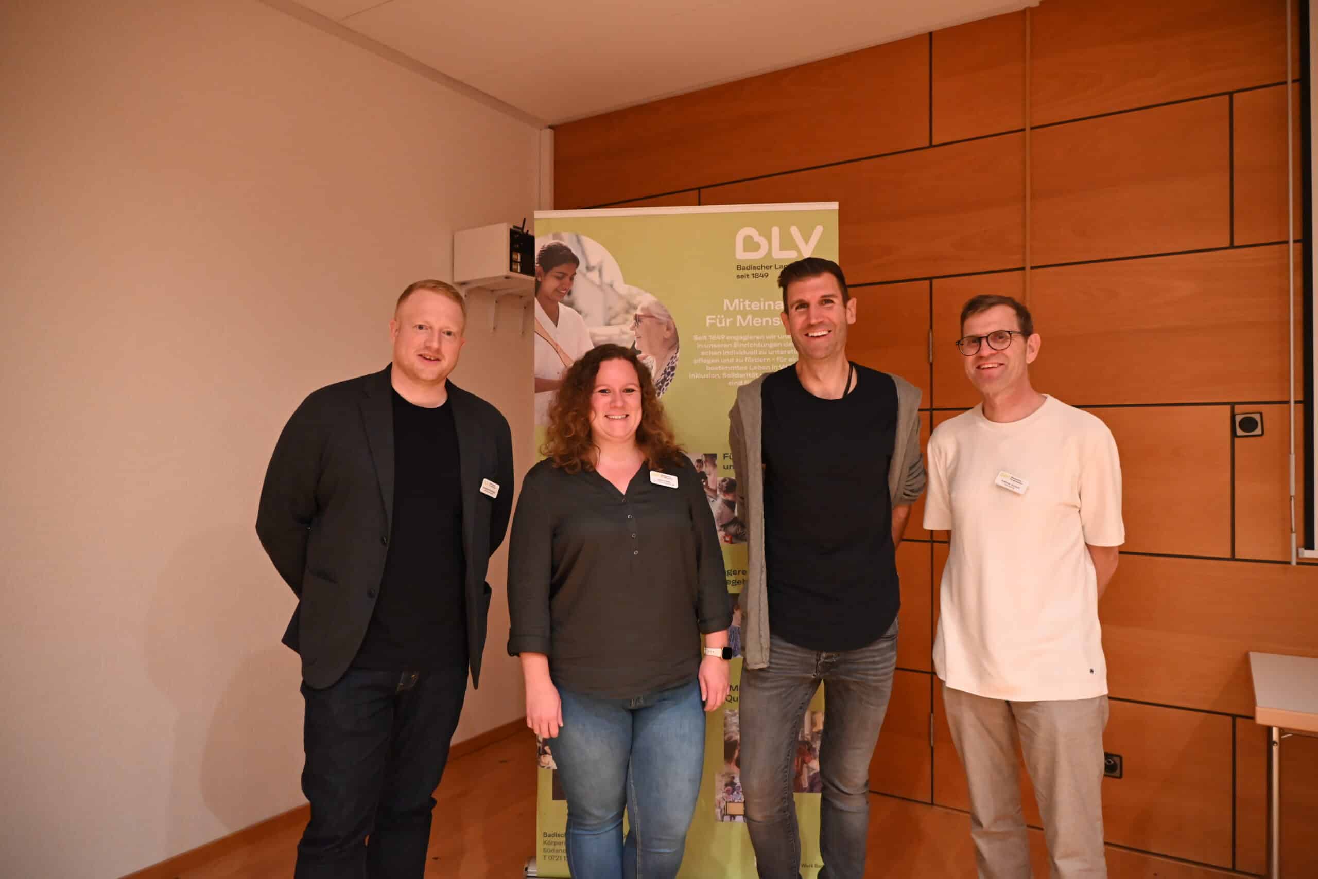 Quelle: BLV Vier Personen stehen nebeneinander, hinter ihnen ein Aufsteller mit Logo des BLV. Von links nach rechts: Christoph Röckinger (Einrichtungsleitung Hohberghaus), Jessica Seitz (stellv. Einrichtungsleitung Hohberghaus), Referent Christoph Boswyk, Andreas Gerlach (Bereichsleitung ambulante und präventive Hilfen).