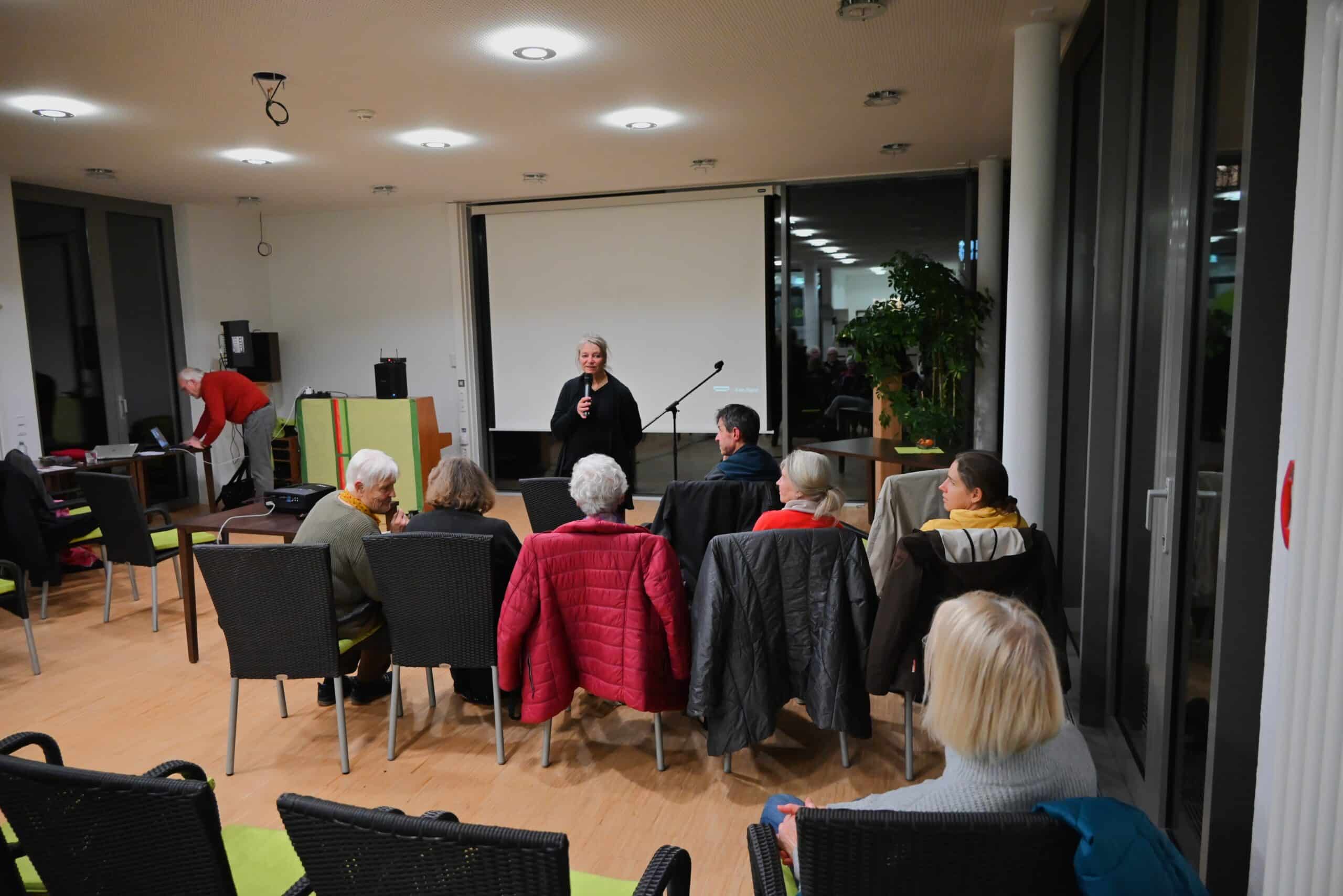 Annette Weiß steht vor Menschen unterschiedlichen Alters und führt eine Gesprächsrunde.