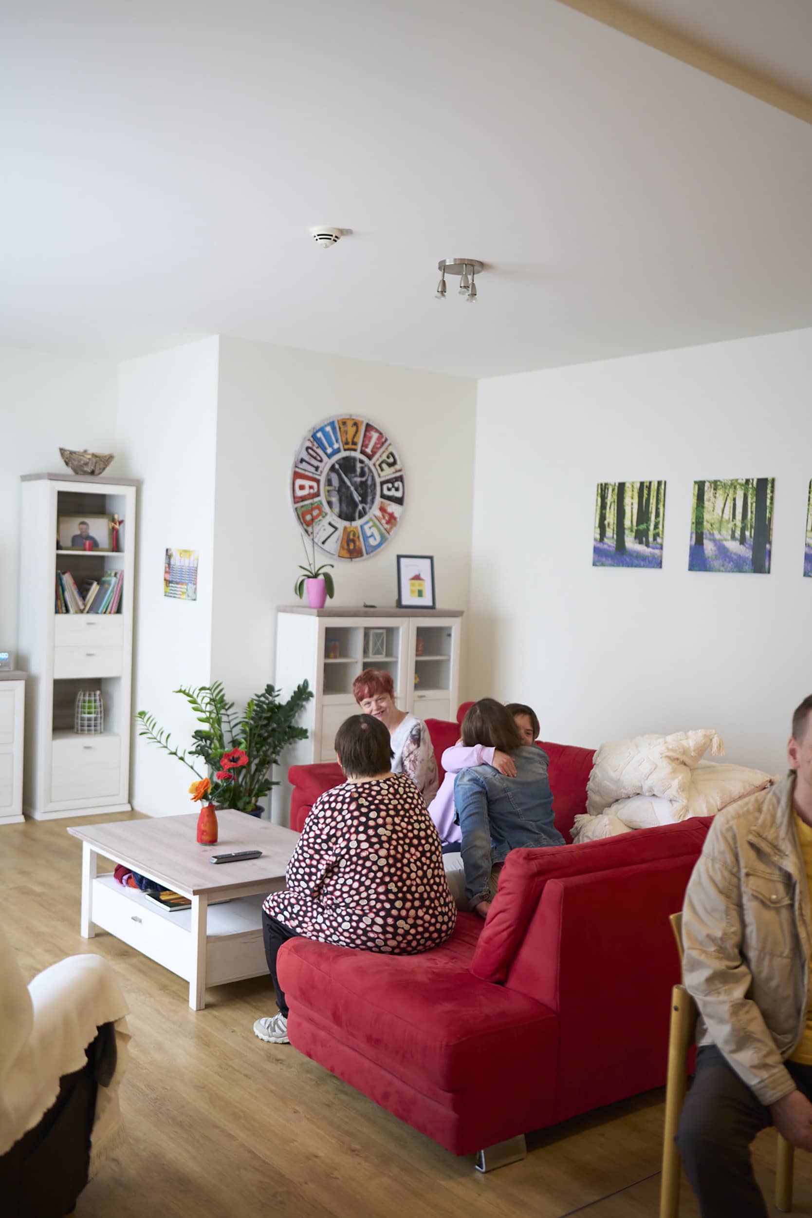 Vier Frauen sitzen im Wohnzimmer auf einem roten Sofa und unterhalten sich.