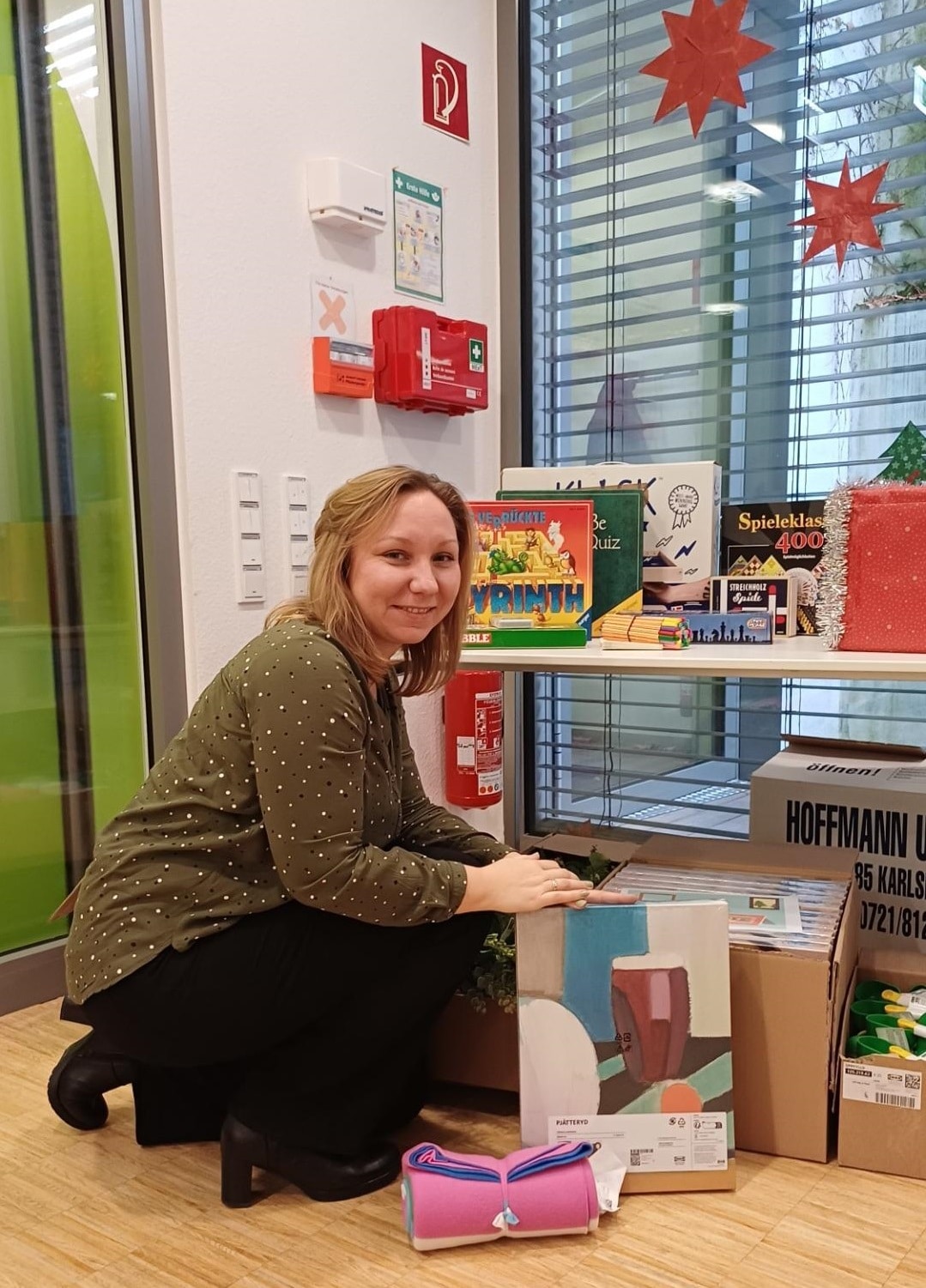 Eine Frau kniet vor einem Tisch voller Weihnachtsgeschenke und lächelt.