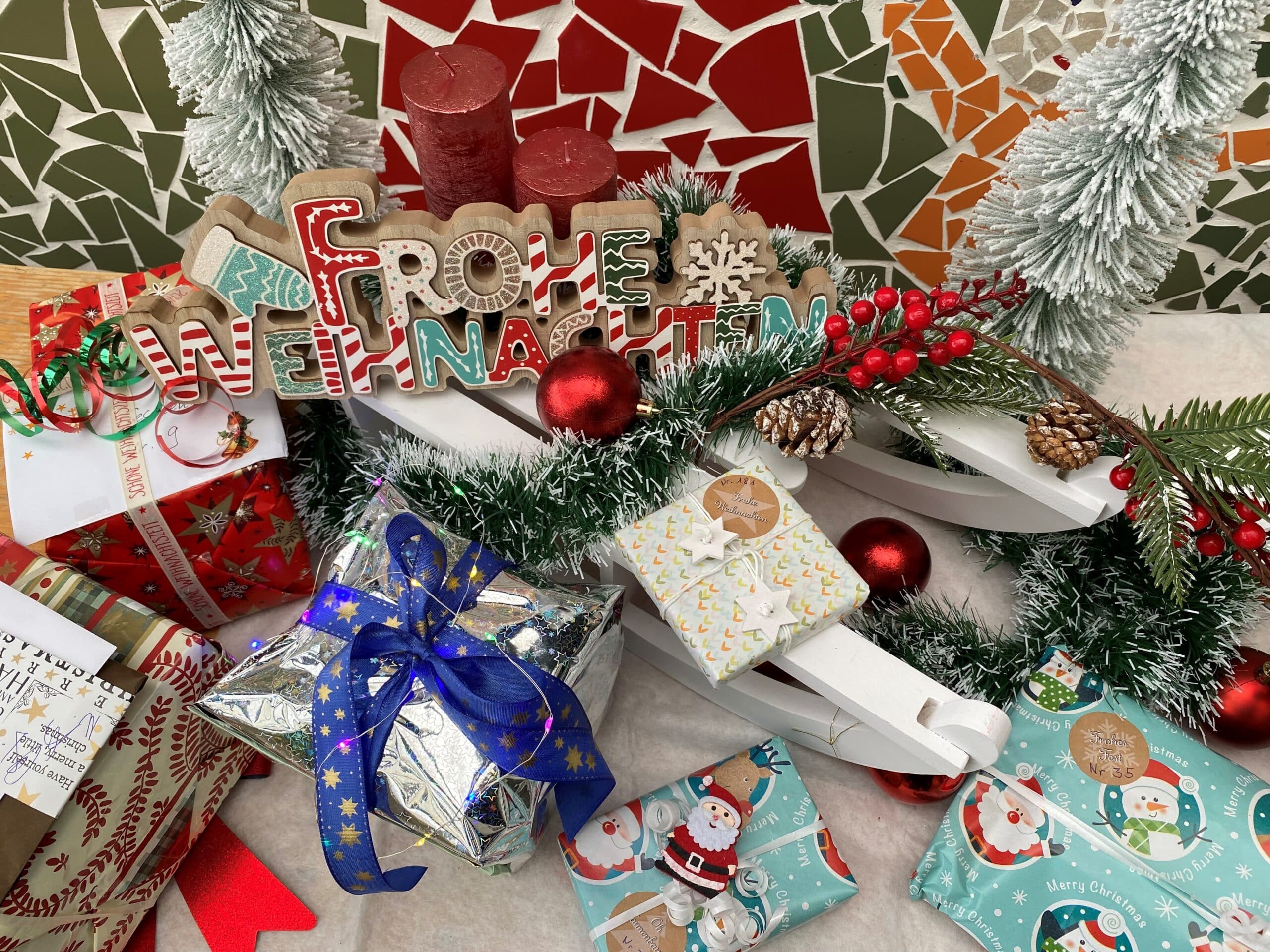 Festlich geschmückte Weihnachtsgeschenke liegen zwischen diverser Weihnachtsdekoration auf einem Tisch.