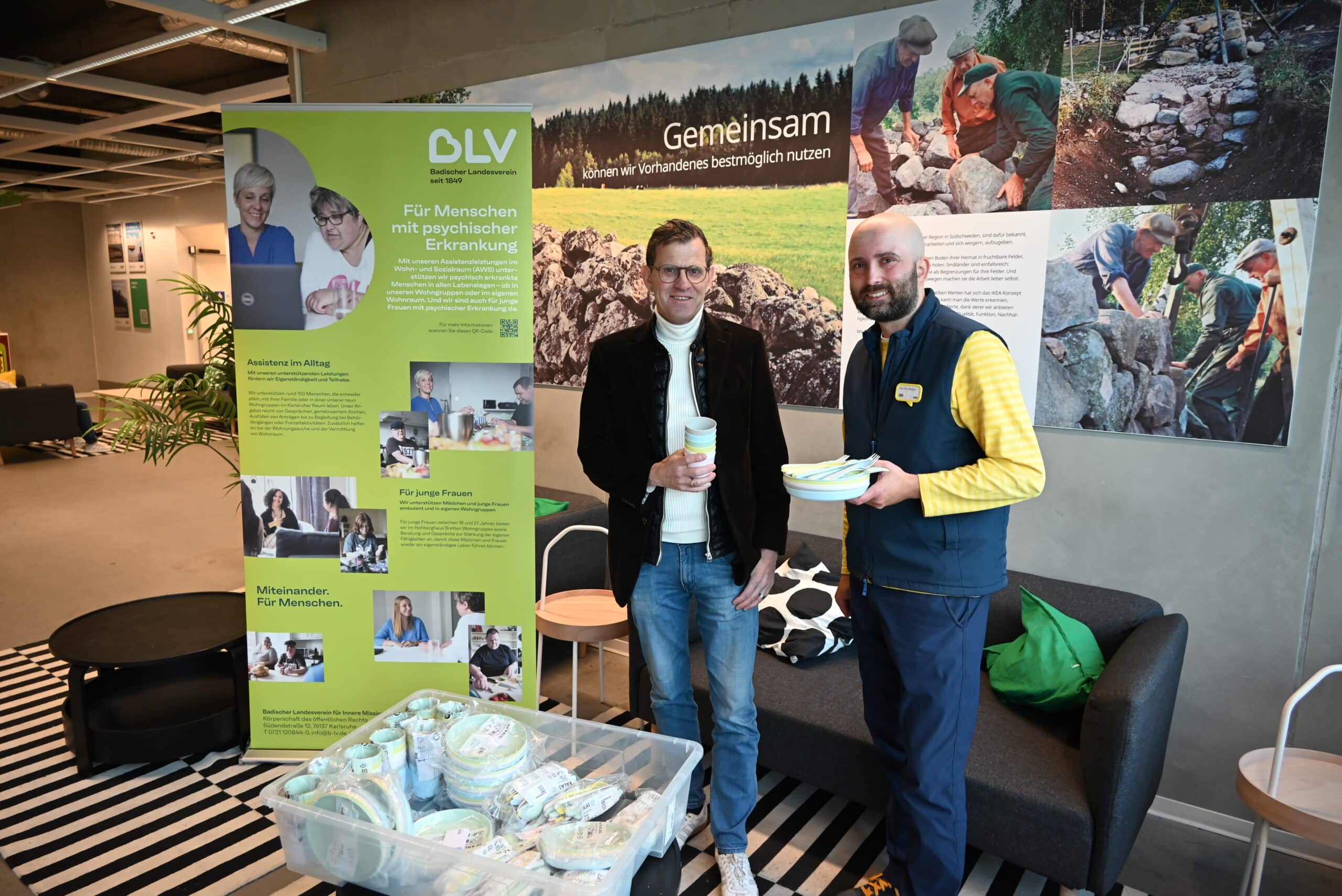 Zwei Männer lächeln in die Kamera und stehen vor einem IKEA Plakat und einem BLV Roll-Up in hellgrün.