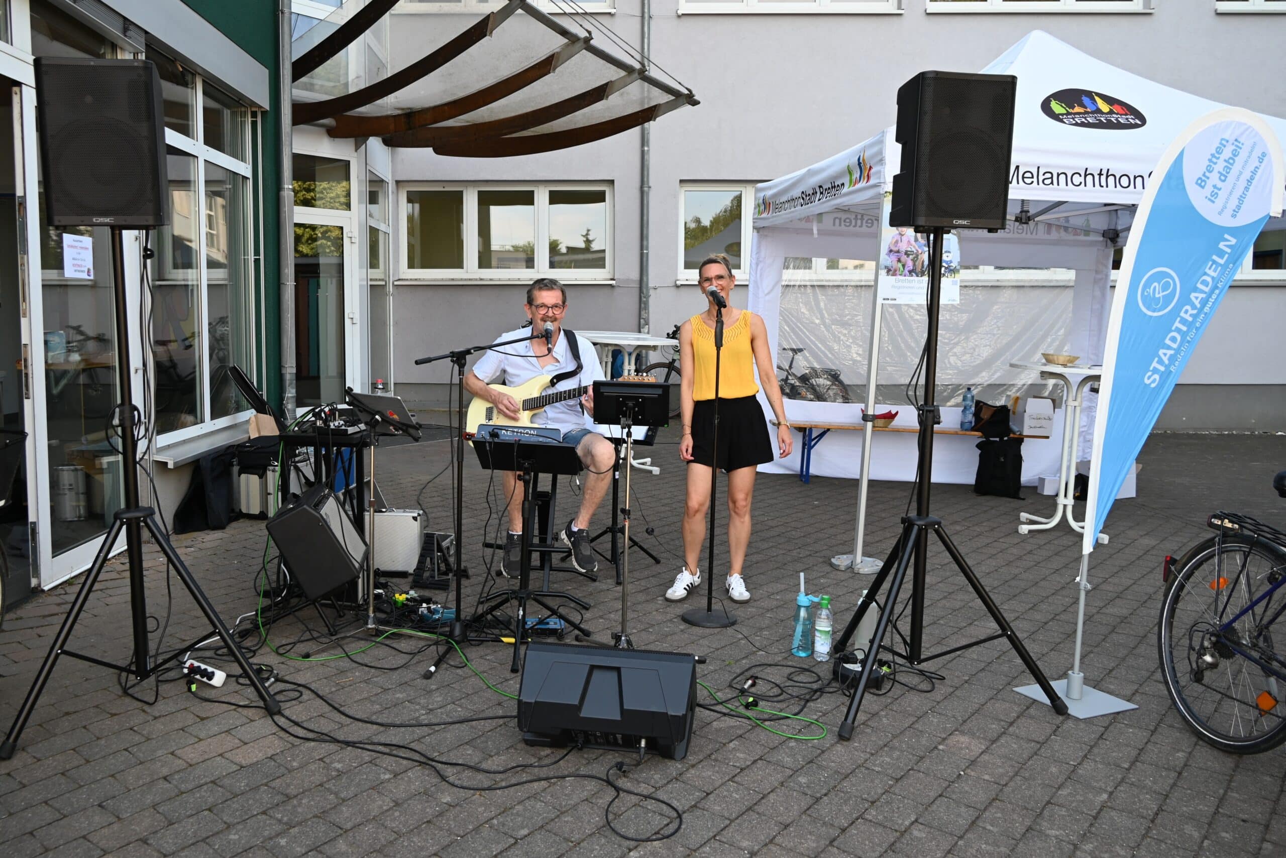 Ein Mann an der Gitarre und eine Frau am Mikrofon singen als Duo